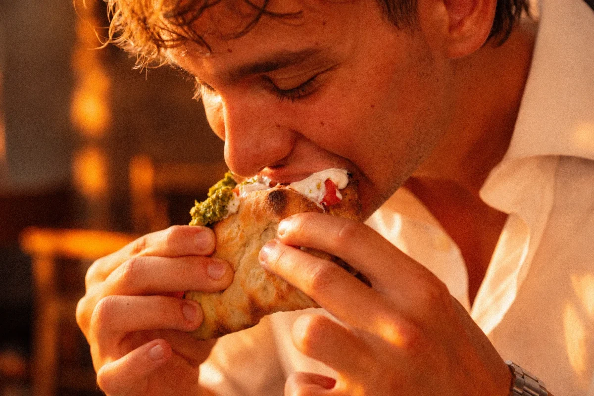 Ragazzo che addenta il Pins8 — il panino farcito di Perdinci