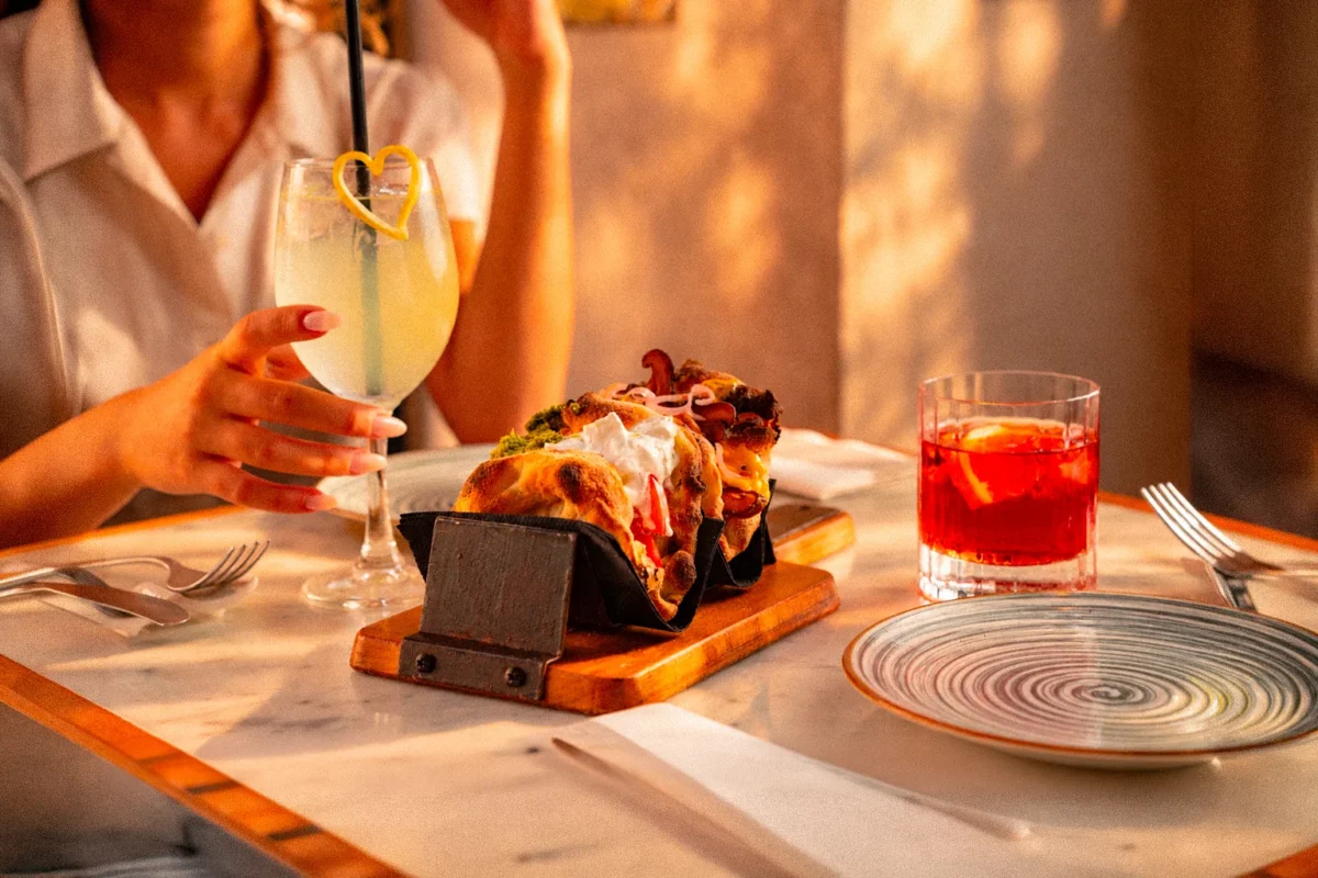 Un piatto signature di Perdinci Bistrò — pinsa con ingredienti freschi e un drink